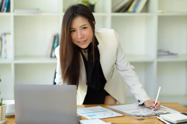 istock Attractive asian secretary leaning on table and working on her assignment. 1366908648