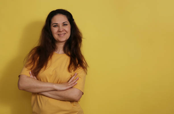 黄色のスタジオの背景にtシャツを着た30〜35歳の女性のベルトの肖像画。 - 35 40 years women female smiling ストックフォトと画像