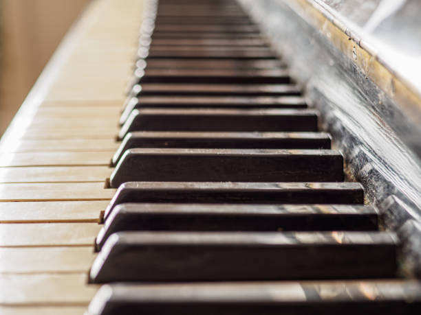 istock Close side view of shiny black and white old piano keys. 1366910665