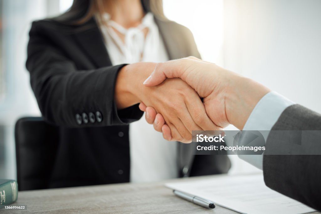 Shot of two lawyers shaking hands in greeting What can I do to help Handshake Stock Photo