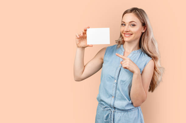 Happy beautiful casual woman holding a blank card isolated on color background Happy beautiful casual woman holding a blank card isolated on color background, close up beautiful women giving head stock pictures, royalty-free photos & images