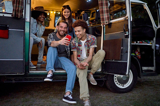 Full length front view of smiling Hispanic, African-American, and Black men and women in their 20s wearing casual weekend clothing and staying connected.