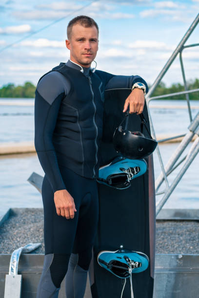 istock Confident wakeboarder in wetsuit standing on pier leaning on board 1366917743