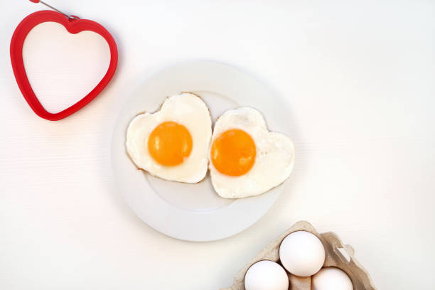istock Romantic breakfast. Heart shaped fried eggs on a plate. white background, flat lay, copy space. Valentines day breakfast idea. 1366919086