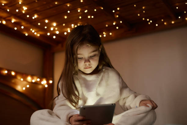 istock A little girl sits with a tablet on the bed 1366921083