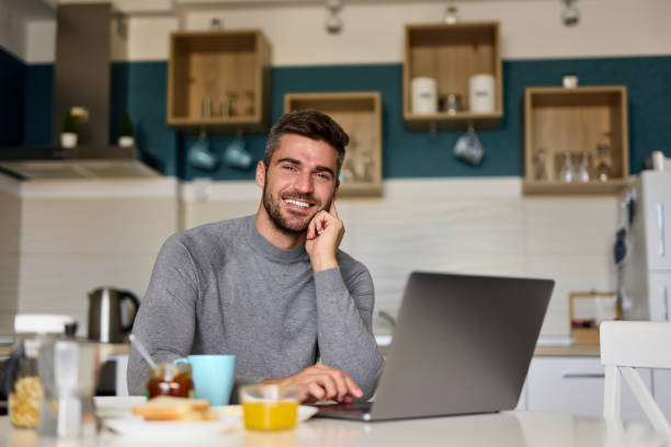 istock Portrait of a young man using a laptop while having breakfast at home 1366922635