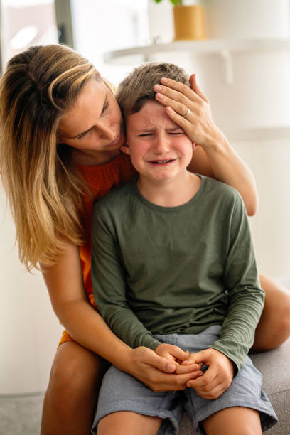 Portrait of mother consoling her crying sad injured son. Child family support parent concept stock photo