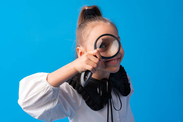 istock Little girl looking through a magnifying glass on blue background 1366923857
