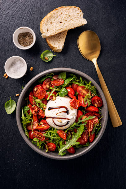 burrata con pomodori, rucola e pinoli. - mozzarella tomato antipasto appetizer foto e immagini stock