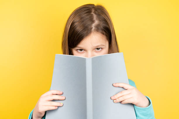 istock Little girl looking to camera with book 1366924700