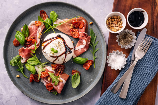 burrata-käse mit parmaschinken und salatblättern. - parmaschinken stock-fotos und bilder