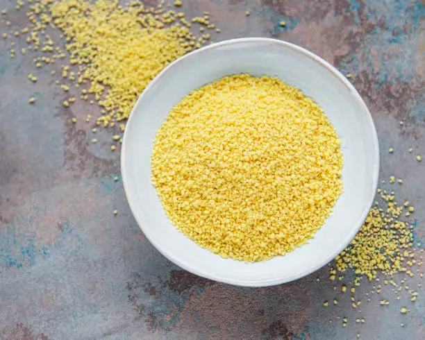 Raw Couscous in a white bowl  on the grey concrete background