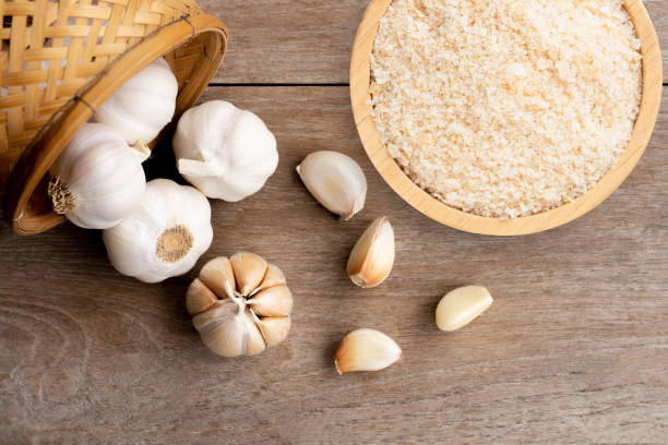 Garlic powder Garlic powder in wooden bowl and bulb of garlic isolated on wooden table background. Top view. Flat lay. garlic stock pictures, royalty-free photos & images