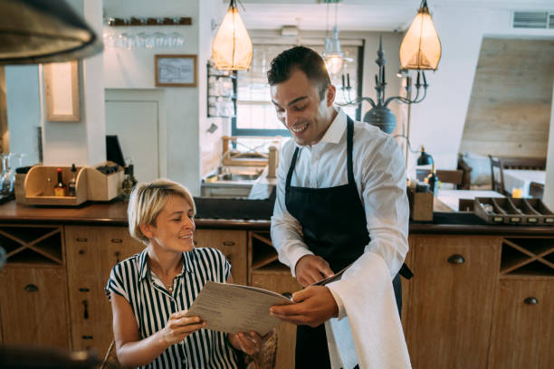 istock Waiter helping a customer to choose food from the menu 1366929061