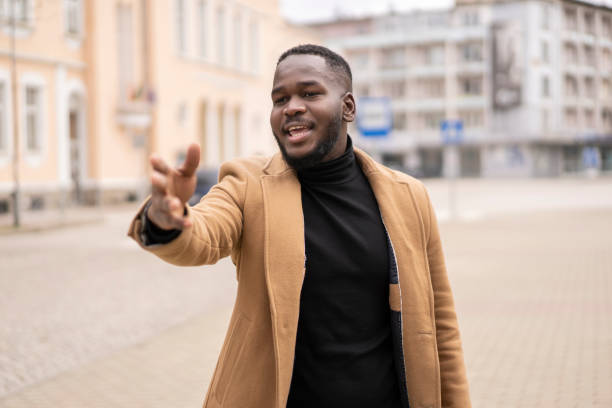 istock A smiling man standing outside holding his arm out 1366929945