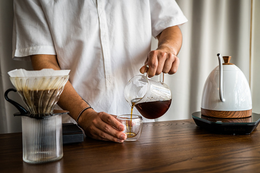 Asian (Thai) man prepares pour over drip coffee beverages at a cafe in Thailand