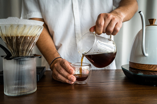 Asian (Thai) man prepares pour over drip coffee beverages at a cafe in Thailand