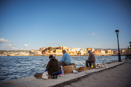 Chania, Crete, Greece - October 20, 2021: Fishermen fishing for sea fish at the old Venetian port of Chania.