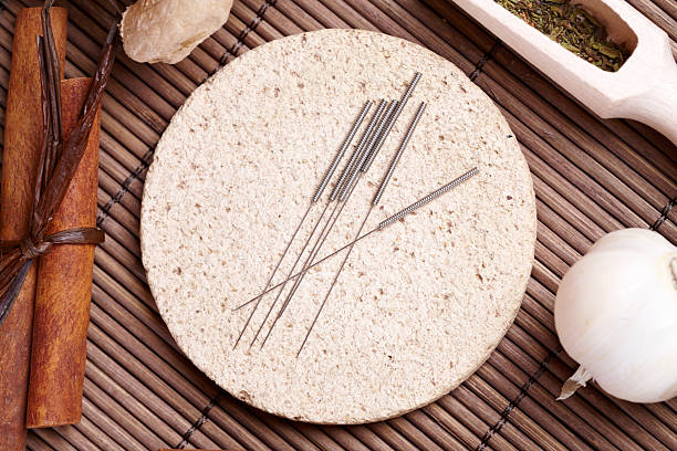 Acupuncture needles and TCM herbs Acupuncture needles laying on the stone mat and herbs like garlic. TCM Traditional Chinese Medicine concept photo acupuncture photos stock pictures, royalty-free photos & images