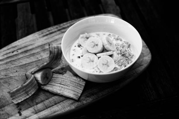 A bowl of breakfast muesli cereal with slices of banana and milk