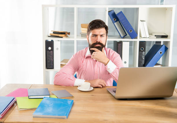 istock Serious man at workplace. Thinking man sitting at office desk 1366931091