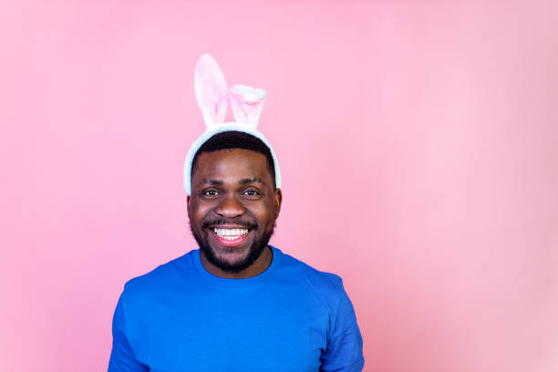 happy young brazil man with bunny ears in studio pink wall background .