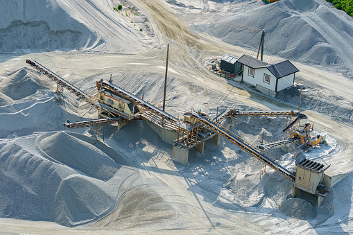 Aerial view of a mining quarry with heavy machinery, surrounded by forest.
