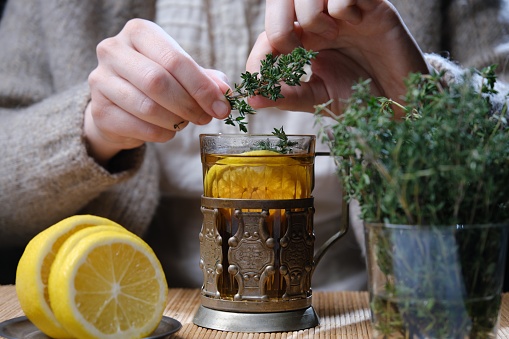 Person is drinking hot tea with lemon, thyme and honey