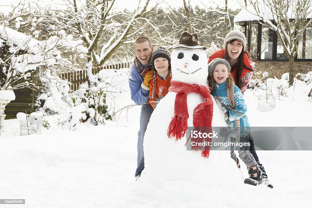 Family Building Snowman In Garden Family Having Fun Together Building Snowman In Garden Family Stock Photo