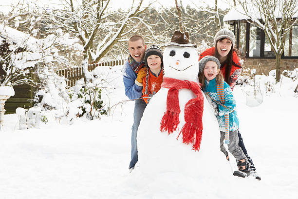 Family Building Snowman In Garden stock photo
