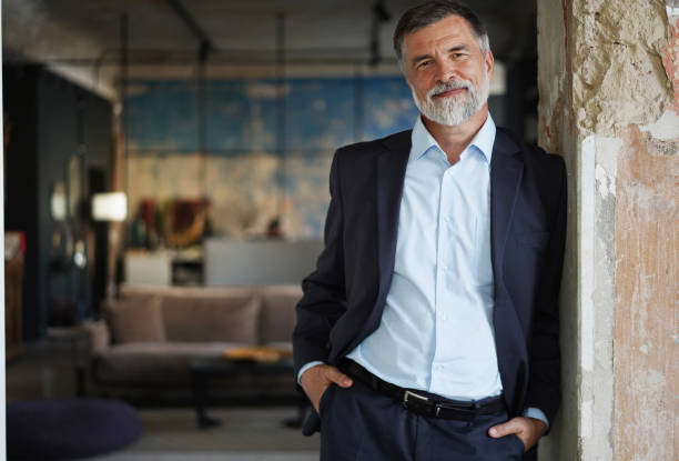 istock Positive confident mature executive man smiling and looking at camera while standing in office 1366936789
