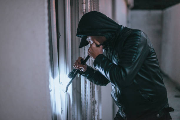 istock Hooded man with flashlight entering into house 1366937873