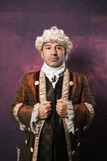 istock Serious man in classic renaissance clothes holding his suit while posing on isolated background. 1366938219