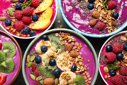 Delicious acai smoothie with toppings in bowls on table, flat lay