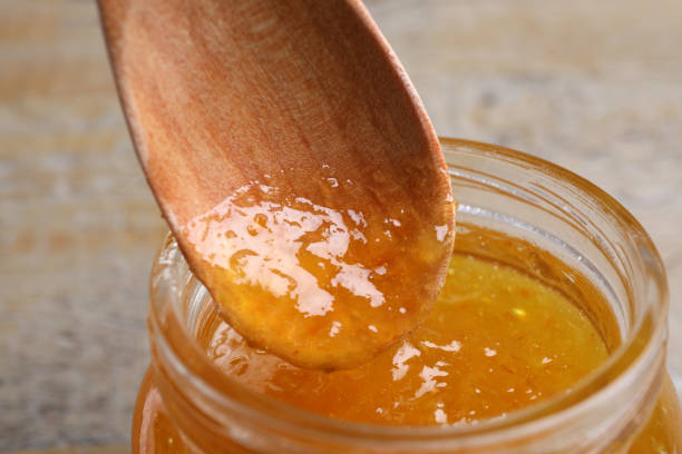 istock Spoon with apricot jam in jar on table, closeup 1366938856