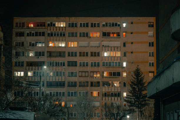 Night shot depicting the glowing, illuminated windows of a Soviet-style apartment block at night in winter.