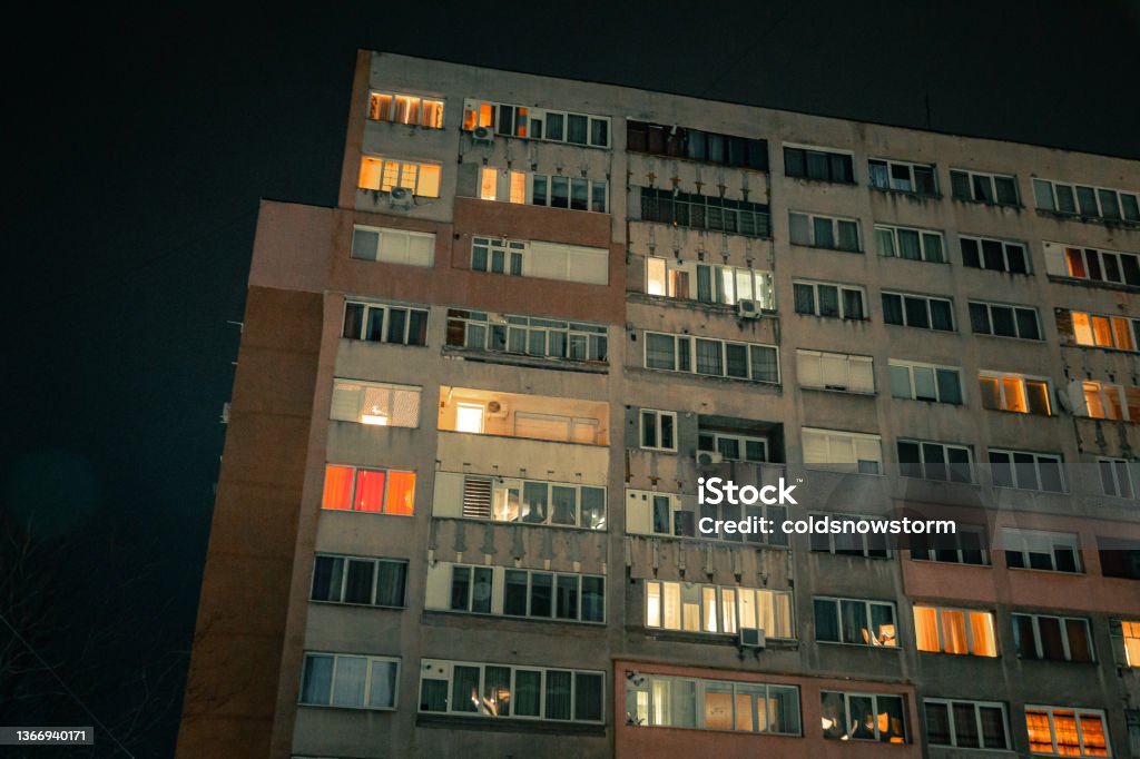 Exterior architecture of apartment block with illuminated windows at night Night shot depicting the glowing, illuminated windows of a Soviet-style apartment block at night in winter. Apartment Stock Photo