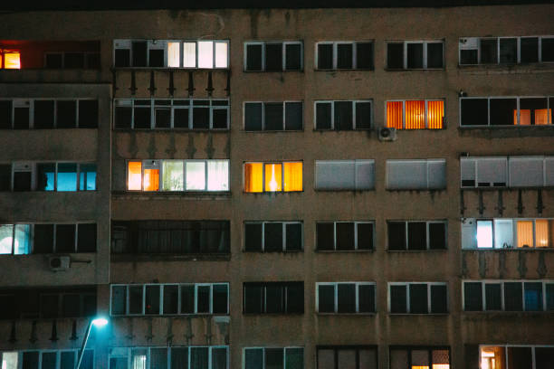 Night shot depicting the glowing, illuminated windows of a Soviet-style apartment block at night in winter.