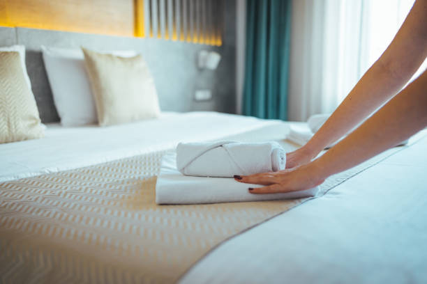 Maid with fresh towels in hotel room.
