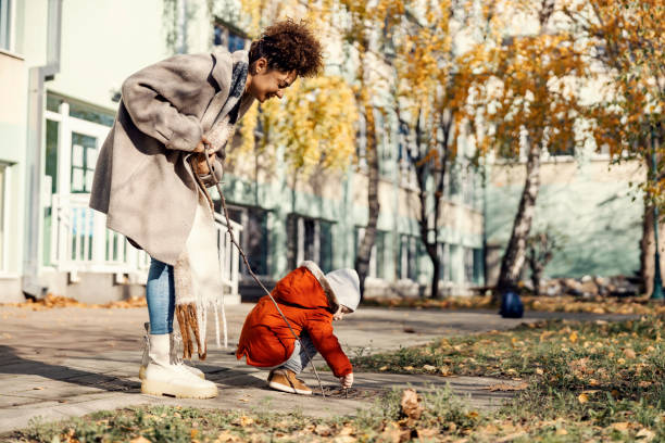 un petit garçon jouant dans la cour d’école avec sa baby-sitter ou sa nounou. - male nurse nurse aspirations learning photos et images de collection