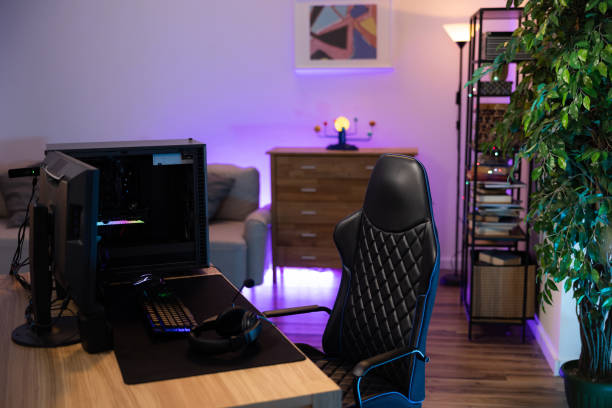 A backlit professional computer for a gamer. The monitor stands on a desk. The cozy room with modern design is lit with purple blue neon led lights A backlit professional computer for a gamer. The monitor stands on a desk. The cozy room with modern design is lit with purple blue neon led lights. neon bedroom stock pictures, royalty-free photos & images