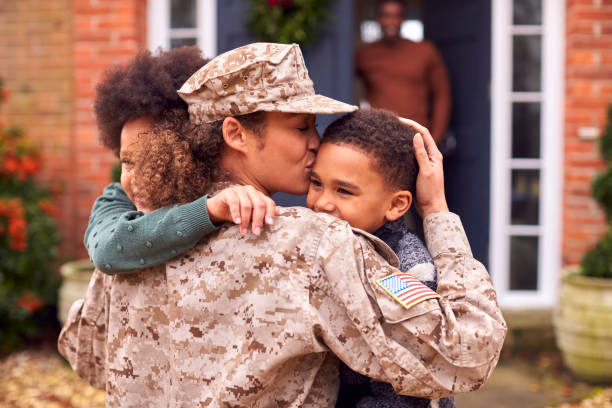 amerikanische soldatin in uniform kehrt nach hause zur familie zurück, um kinder vor dem haus zu umarmen - good defense stock-fotos und bilder