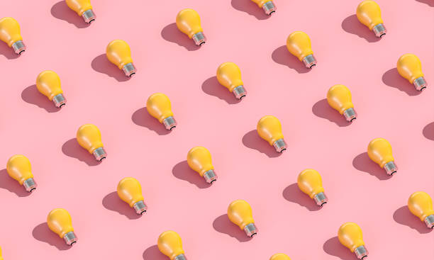 yellow light bulbs on pink background in flat lay style.