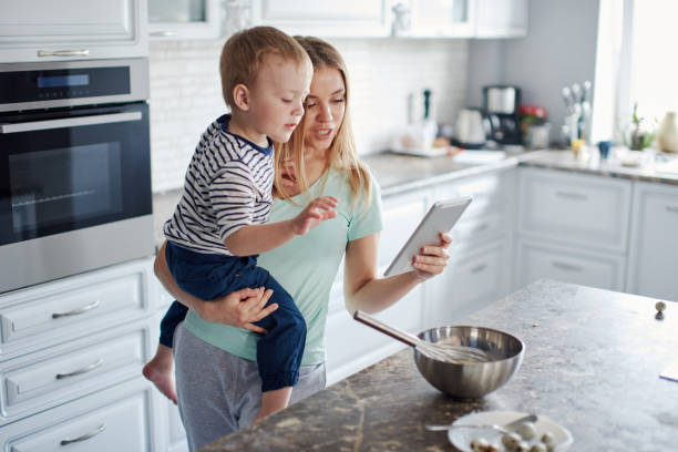 Busy mother with tablet and son in hands stock photo