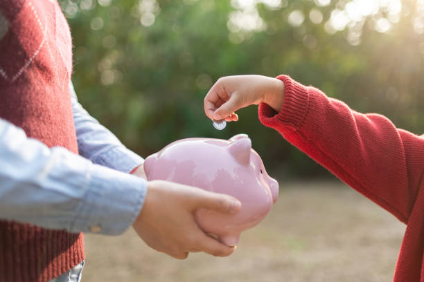 Child puts coins in the piggy bank stock photo