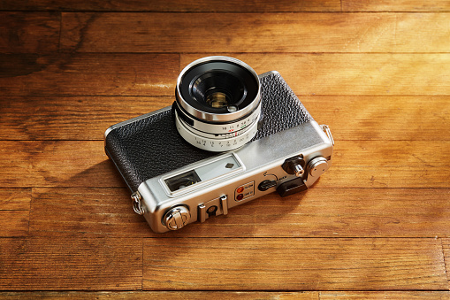 A vintage Japanese camera, its lens prominently featured, catches the light, A vintage Japanese camera, lens in focus captures the light, brilliantly reflecting off its glass; a nod to past eras
