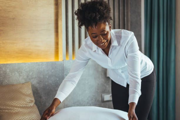 istock Maid making bed in hotel room. 1366947028
