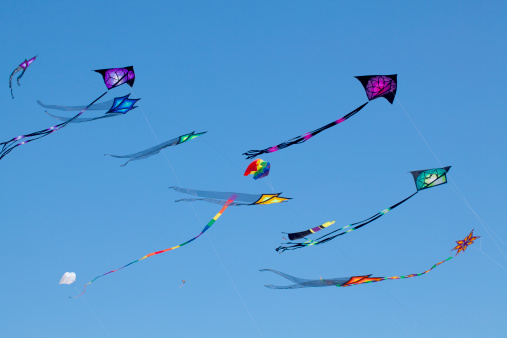 Brightly colored kites sailing against clear blue sky