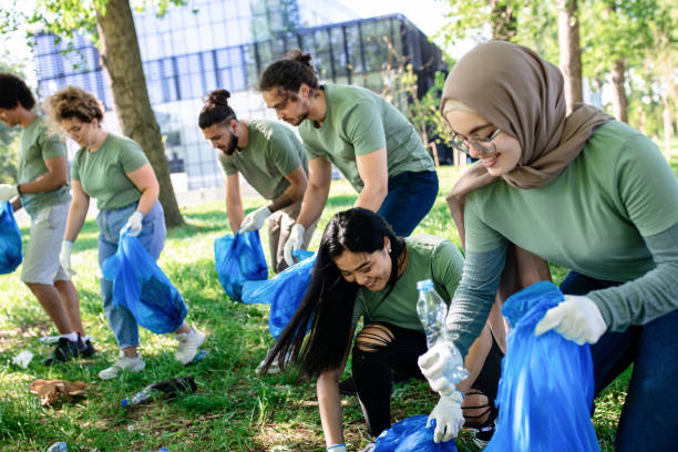 groupe multiethnique de bénévoles avec des sacs poubelles nettoyant le parc de la ville. - bag garbage bag plastic black photos et images de collection