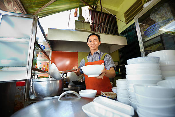 Man cooking and serving soup in bowls at restaurant Chef preparing traditional Asian street food and working in the restaurant kitchen. Horizontal shape, front view cambodian ethnicity stock pictures, royalty-free photos & images
